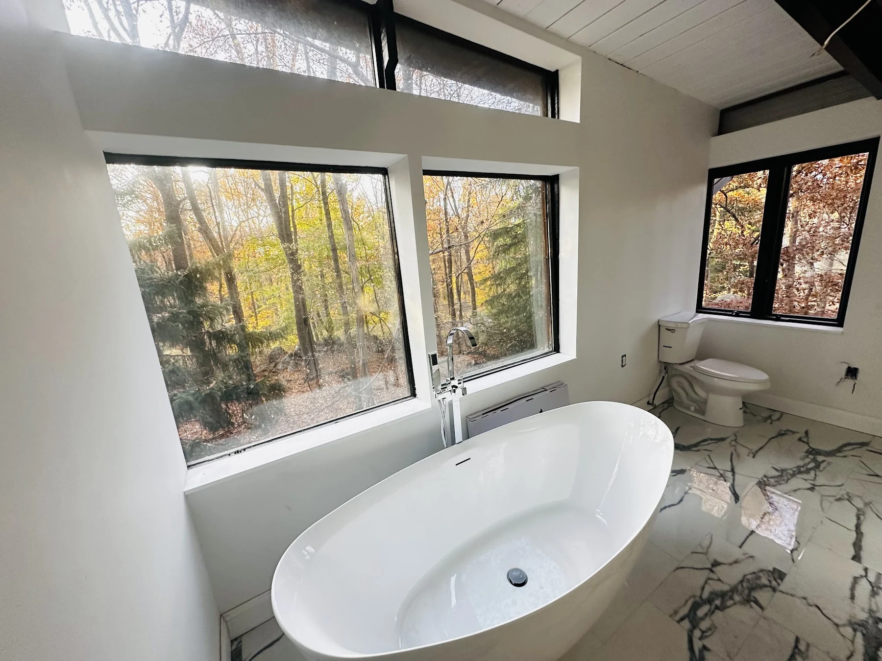 Bathroom renovation with freestanding tub and marble-pattern tile floor