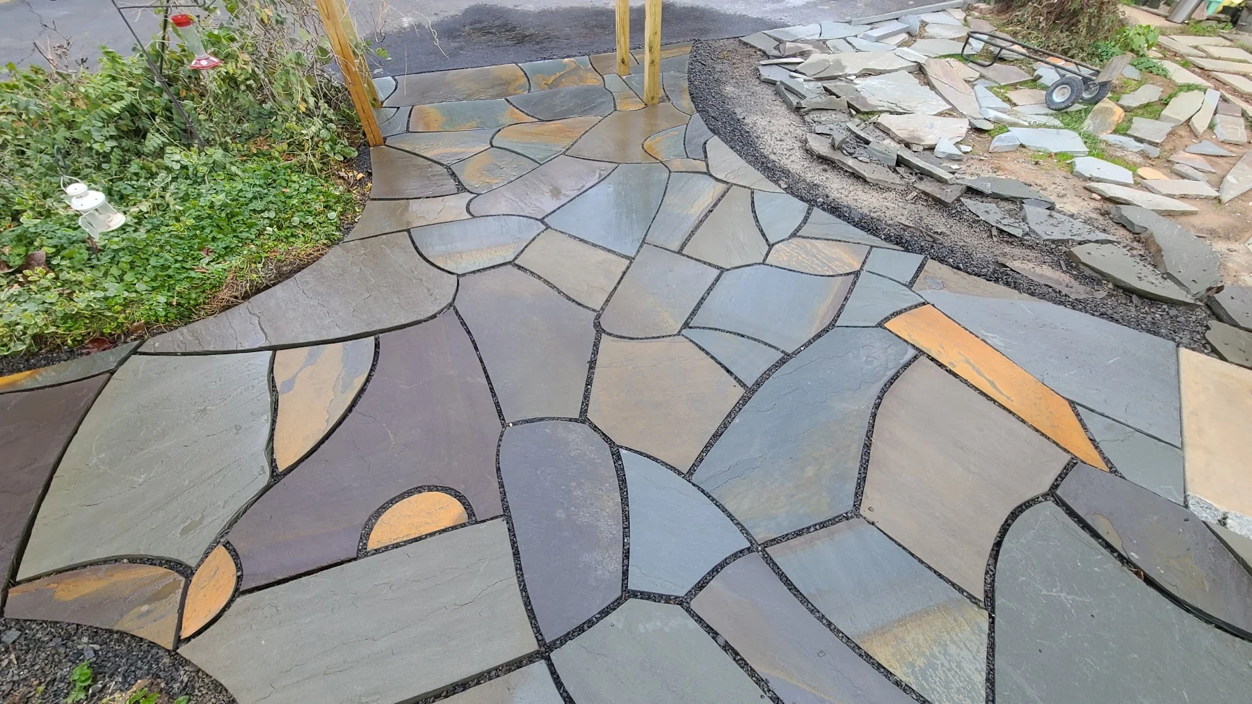 Irregular natural stone fitted along a curved walkway during installation